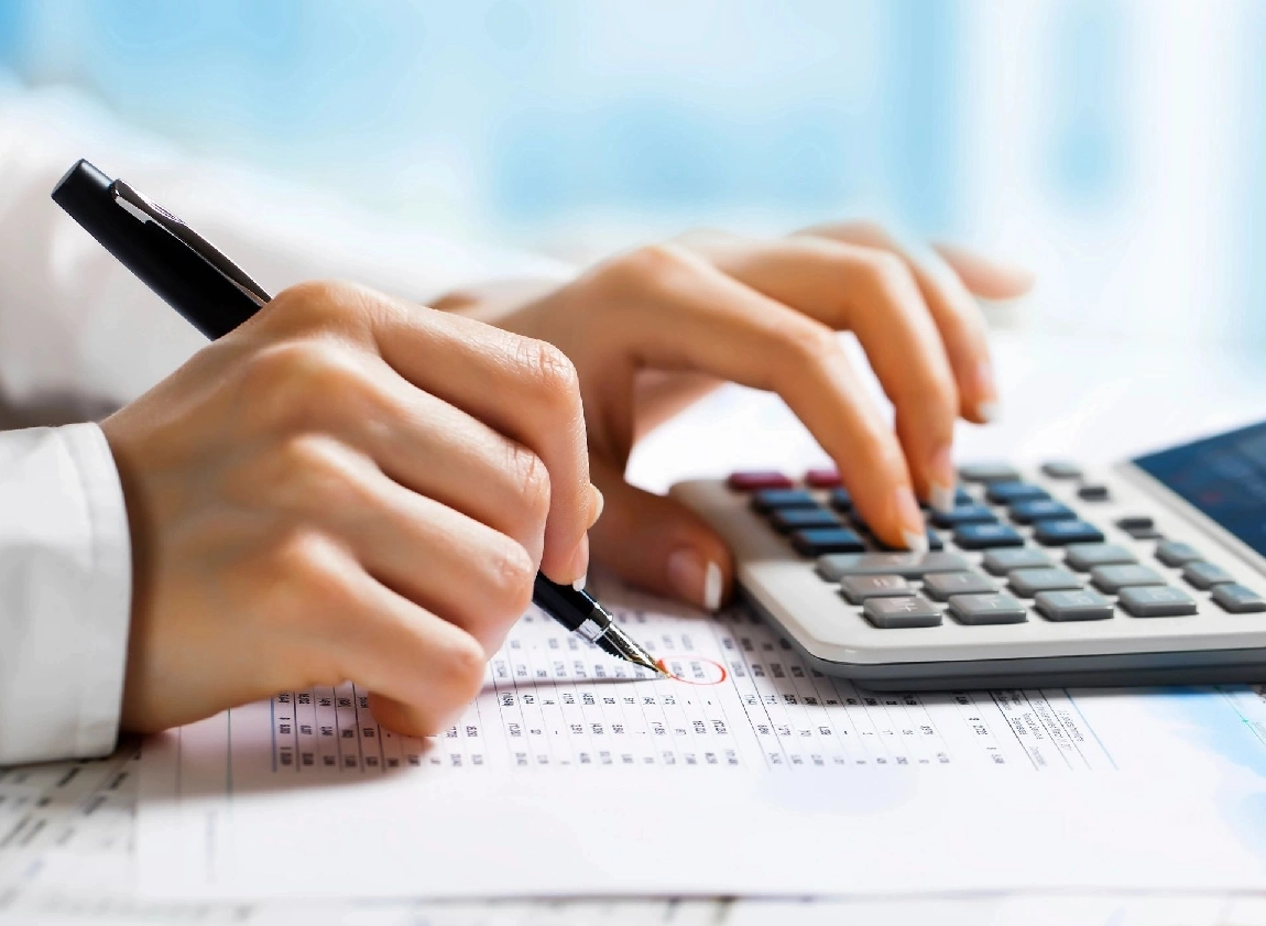 Hands using a calculator and writing on a financial document.