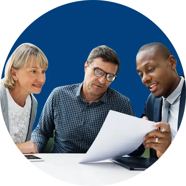 Three people are sitting together reviewing a document. The person on the right, in a suit, is showing the paper to the two individuals on the left. The background is a solid blue color.